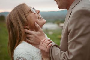 Close up of a romantic moment between two people outdoors with a blurred natural landscape in the background.