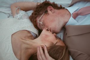 A tender moment between newlyweds lying together outdoors.