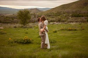 Newlyweds share an intimate moment in a scenic mountain valley surrounded by spring wildflowers.