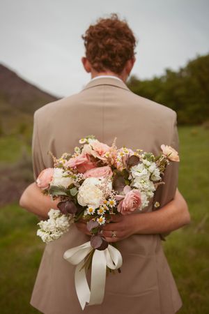 Back view of tan suit jacket with pink and white floral bouquet arrangement.