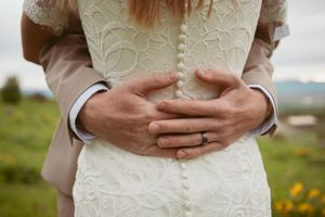 Close-up detail of a lace wedding dress with delicate buttons and embroidery.