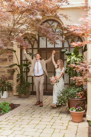 Happy couple celebrates their wedding day in a beautiful courtyard with arched doorways and Japanese maple trees.