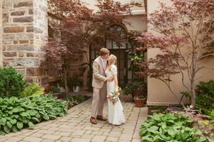 A romantic wedding photography session in a charming brick courtyard with lush greenery and flowering plants.