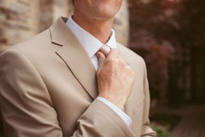 Close-up detail of a tan suit jacket and white dress shirt with a necktie.