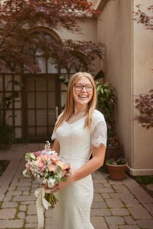 A bridal portrait session in front of stone walls with arched windows and autumn maple leaves.