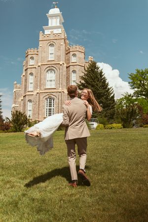 A playful sequence shows a couple dancing and spinning on a grassy hill in front of a historic stone church building.