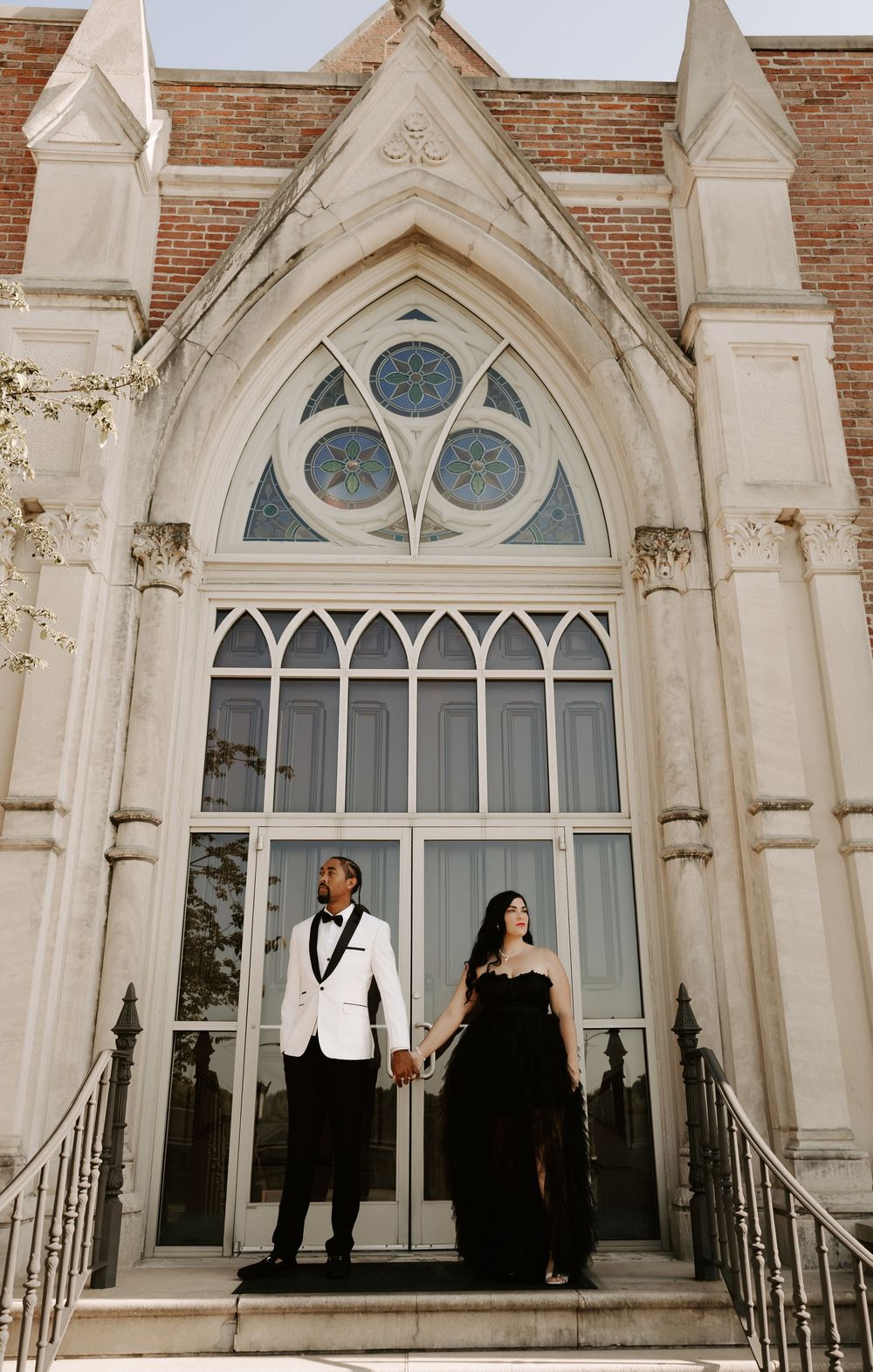 Gothic church windows and architecture create dramatic backdrop for wedding portraits.