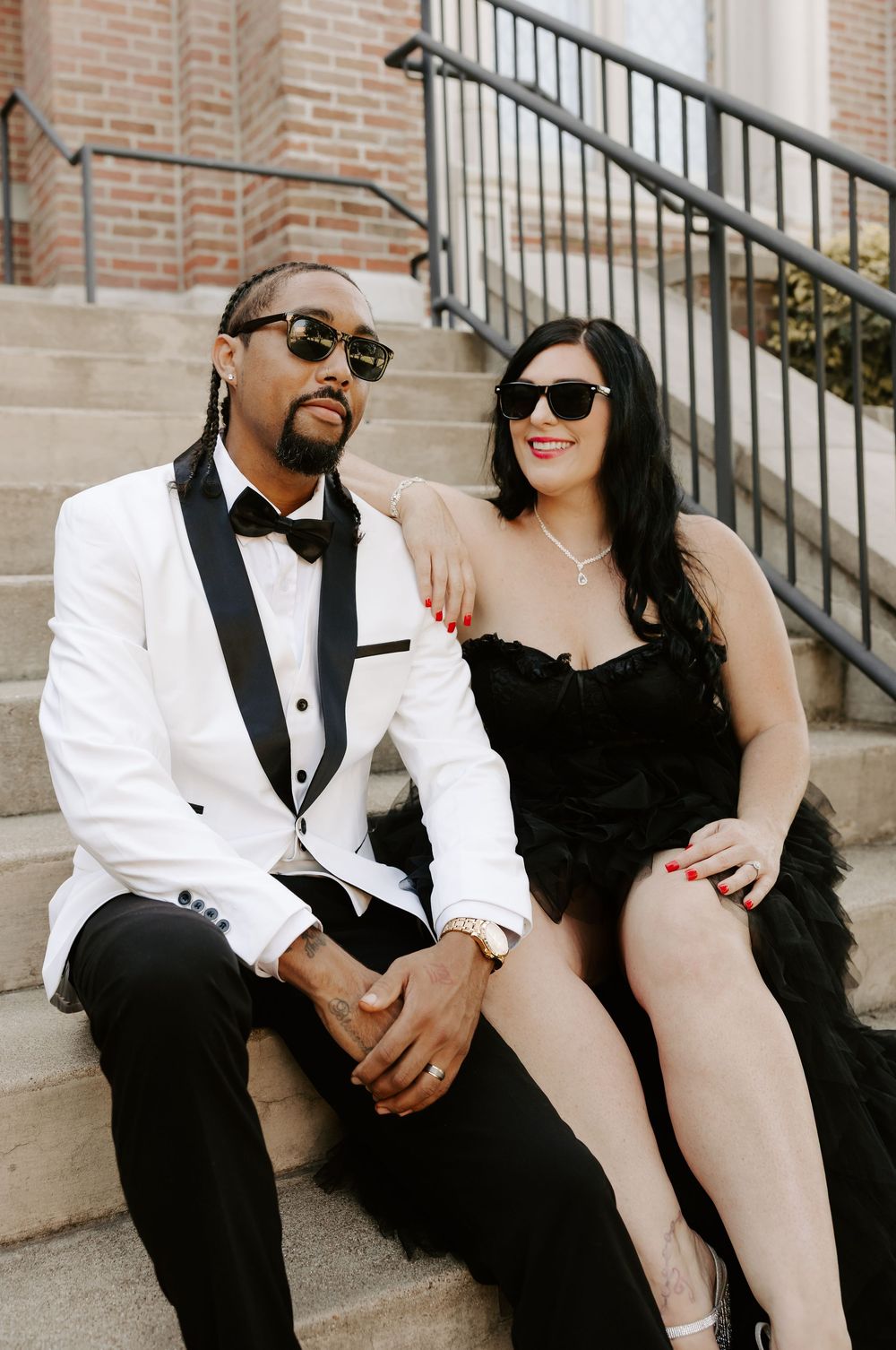 A couple in formal attire relaxes on stone steps during a photo session.