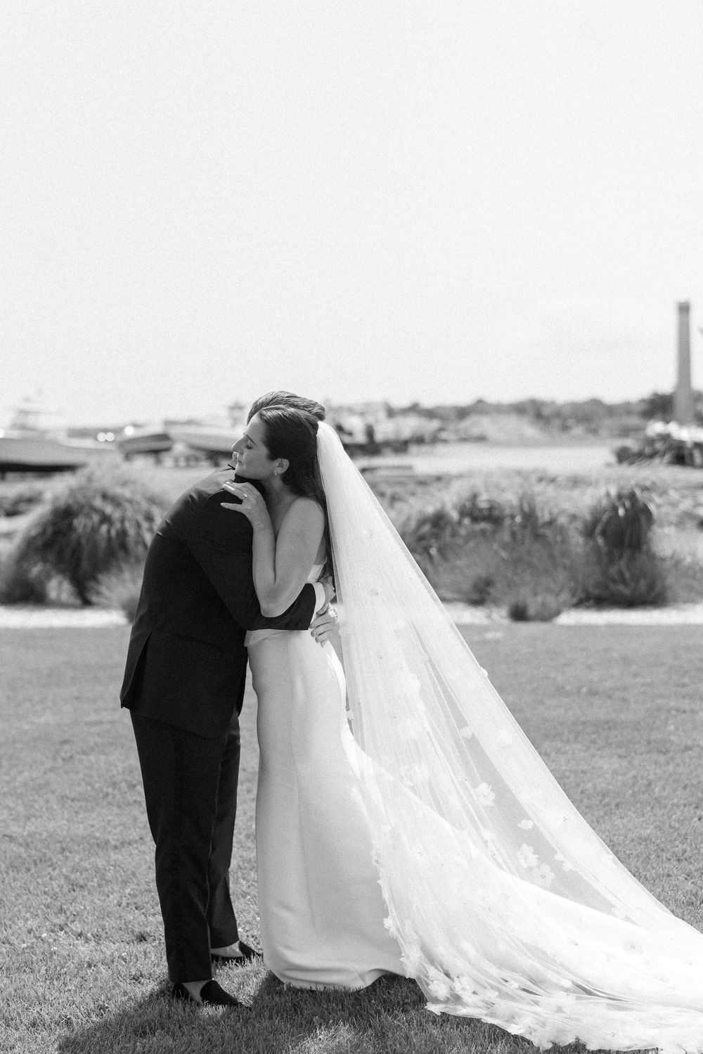 A romantic wedding scene unfolds on a grassy lawn with a long flowing veil.