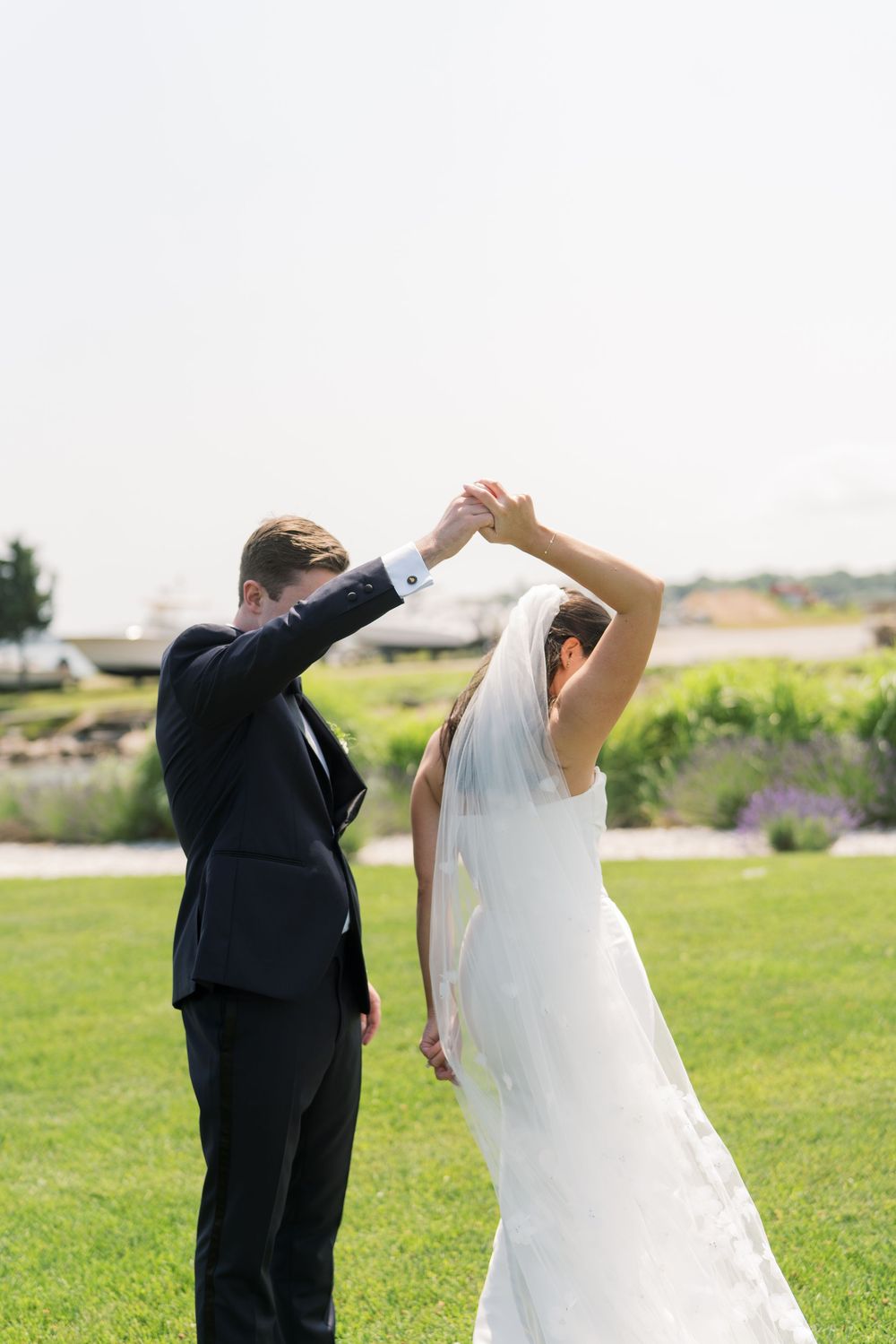 A couple dances together on a grassy lawn during their wedding day celebration.