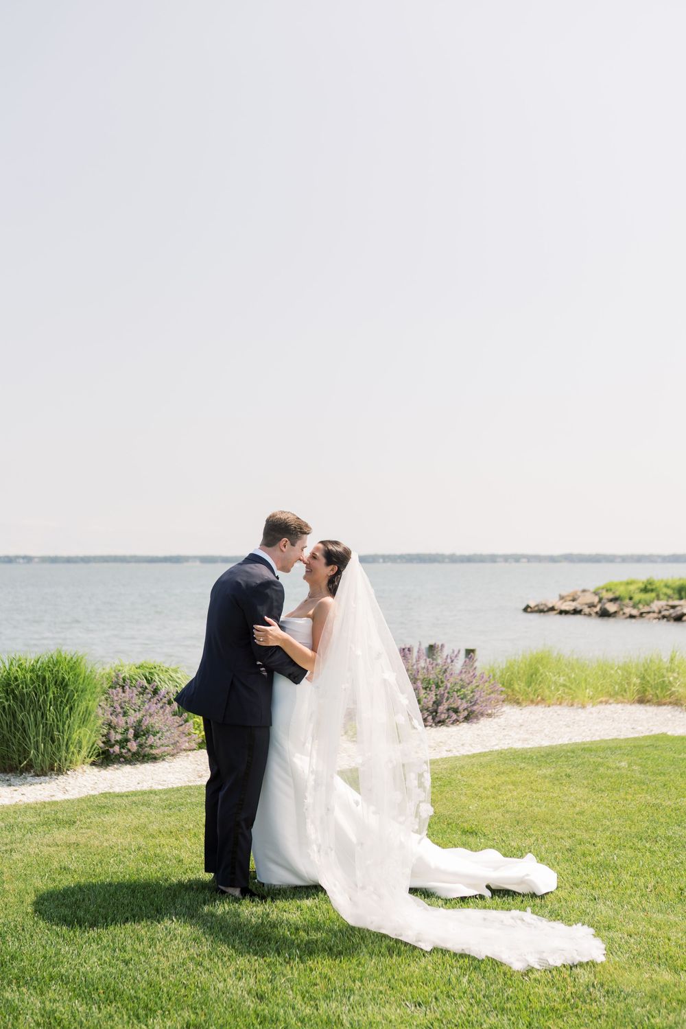 Elegant couple embraces during their waterfront wedding ceremony.