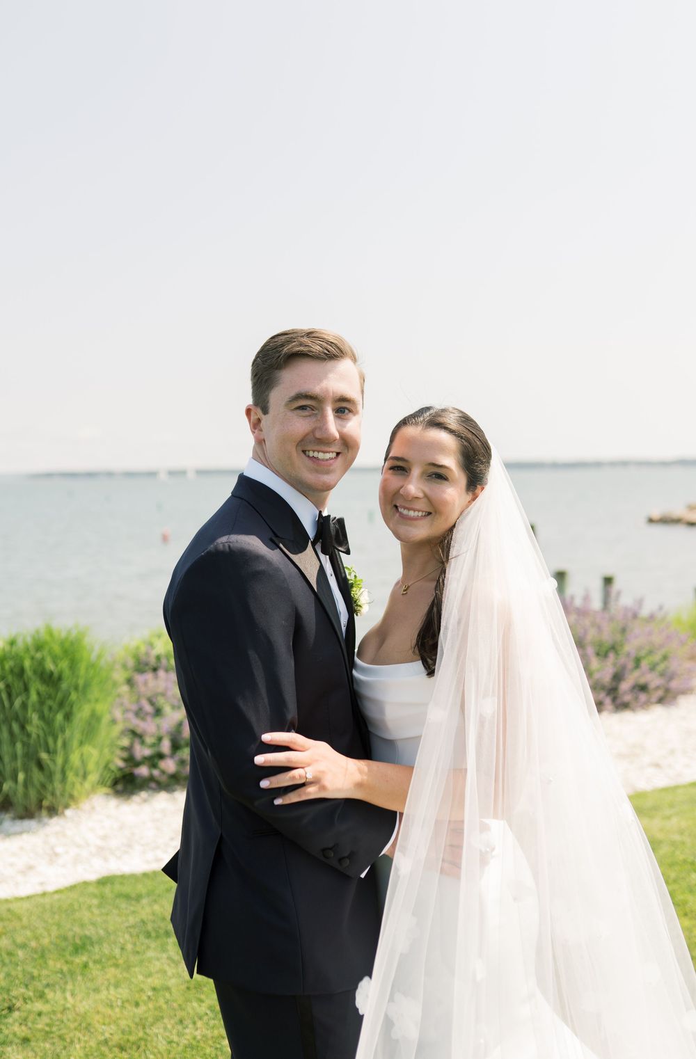 Joyful wedding couple shares a candid moment during their coastal wedding photoshoot.