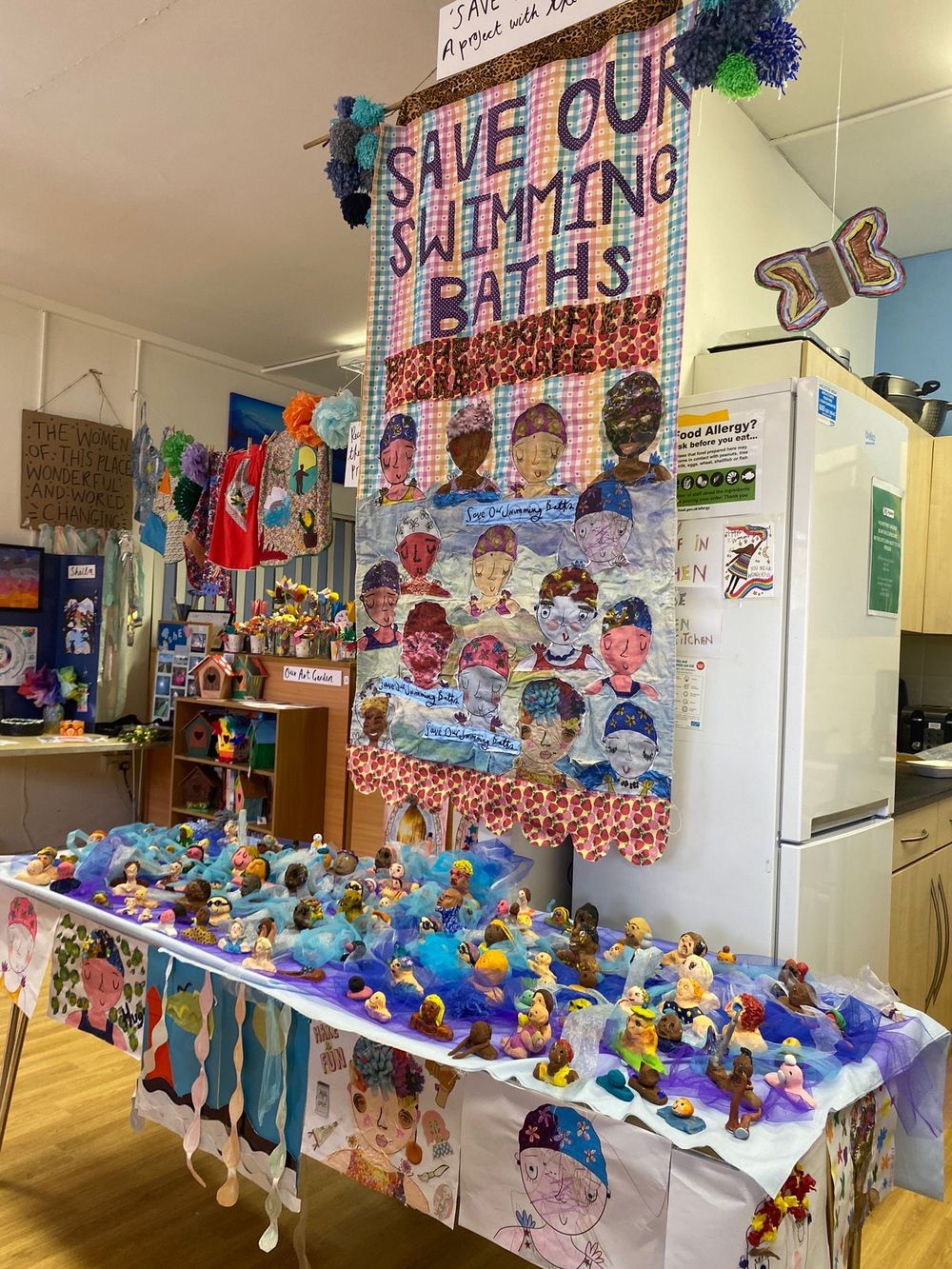 A colorful school display with 'Save Our Swimming Baths' banner and hand-decorated artwork featuring swimming-themed illustrations.