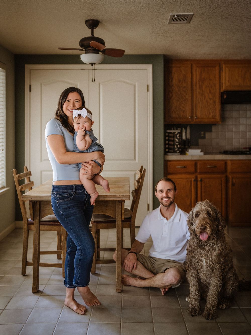 A family gathering in their kitchen with a curly-haired doodle dog joining the scene.