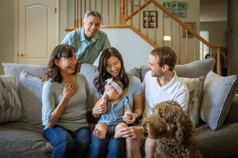 A joyful family moment shared on a comfortable grey couch indoors.