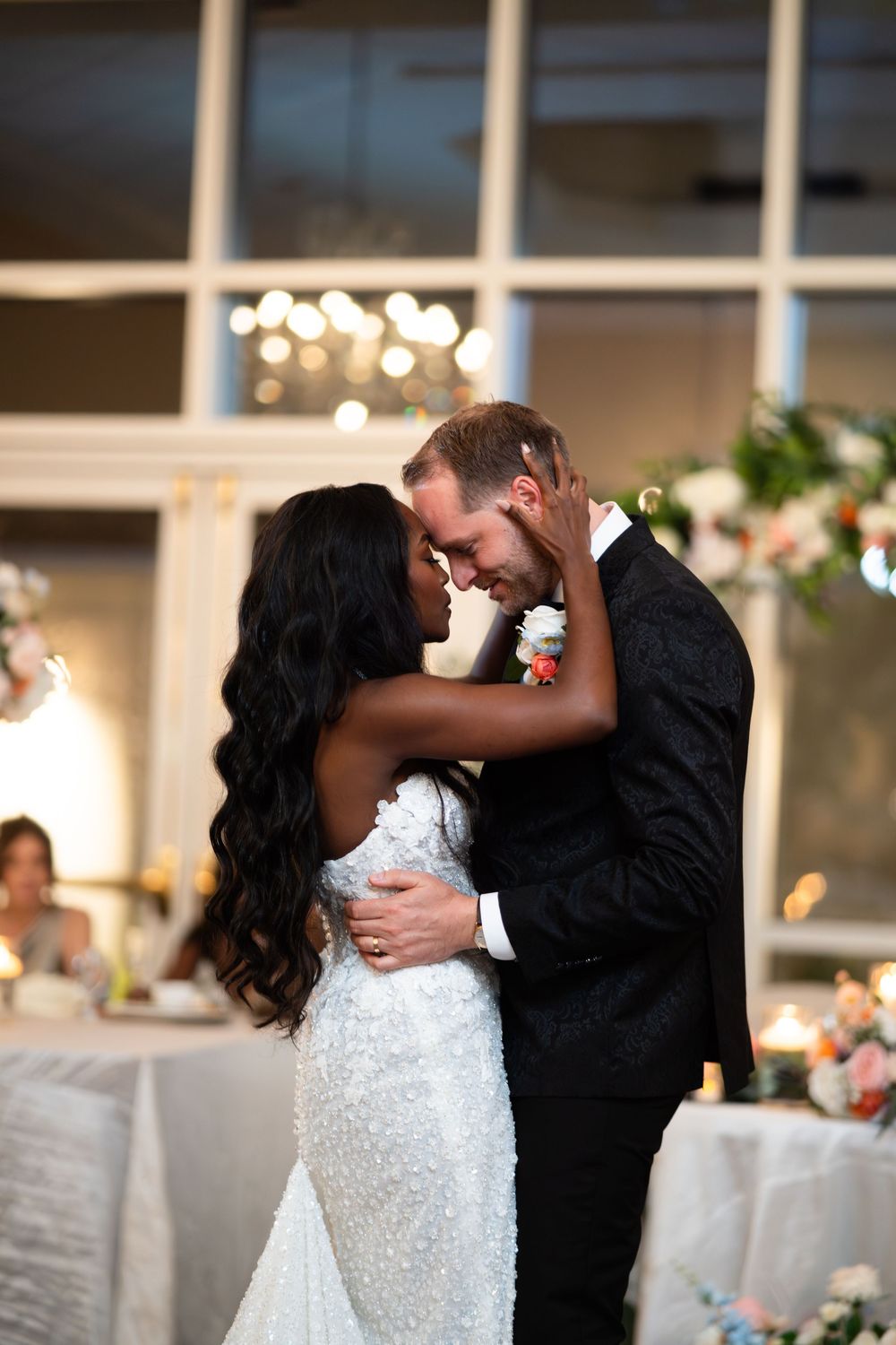 Newlyweds share romantic kisses during their first dance at an elegant indoor wedding reception.