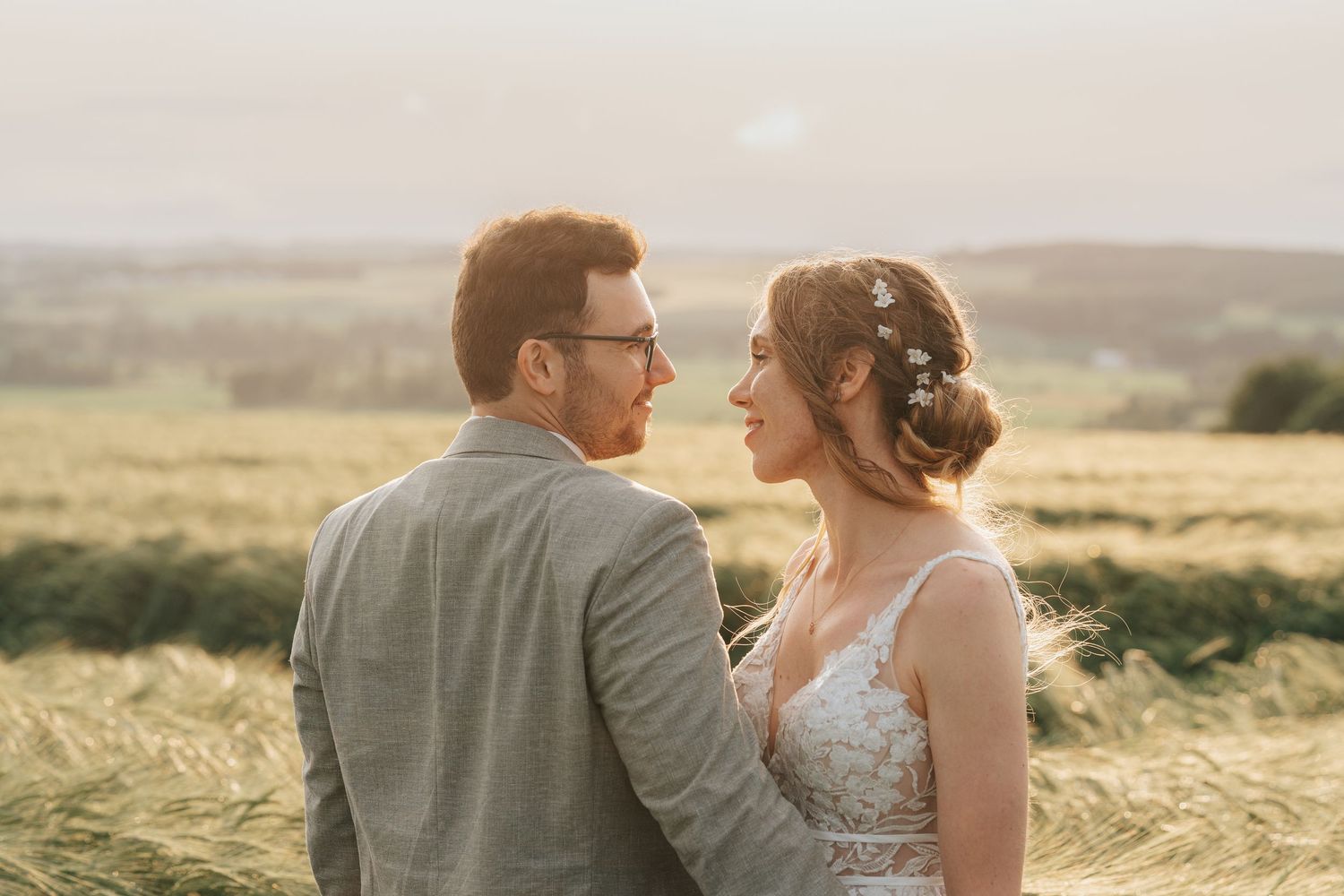 Romantic outdoor portrait in a golden wheat field under cloudy skies.
