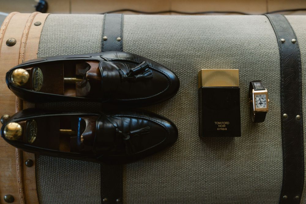 Leather dress shoes and boots displayed in a row on wooden shelving against a gray fabric background.