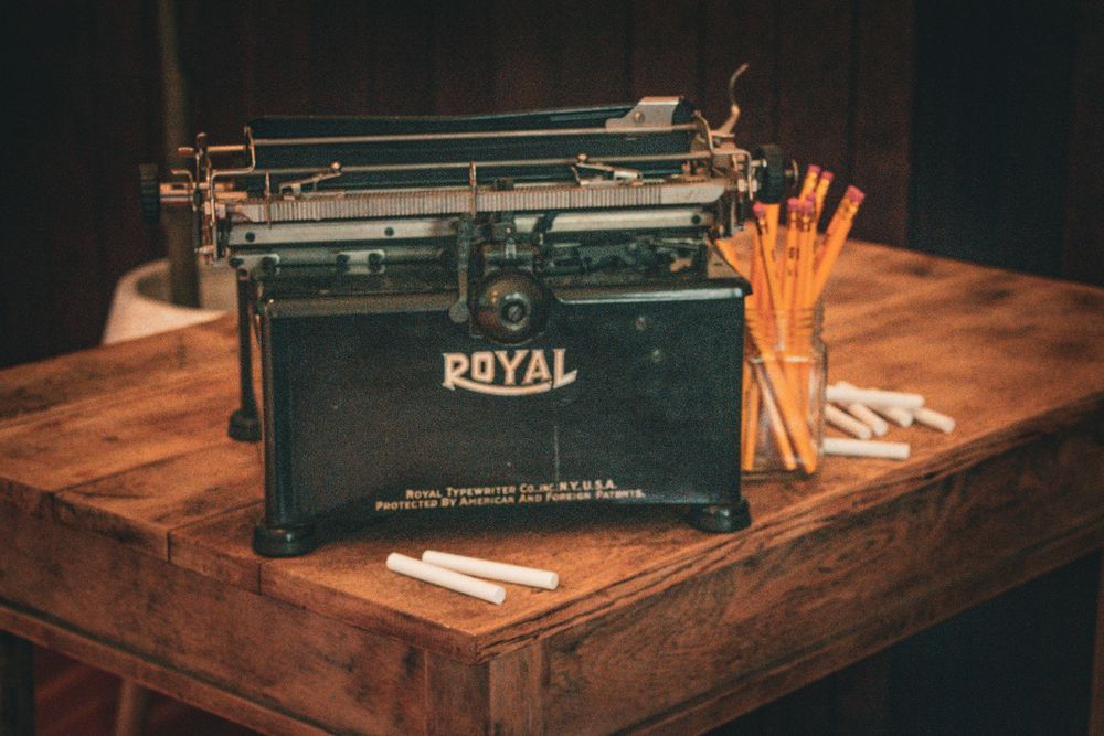 Classic Royal typewriter with pencils on wooden desk in warm lighting.