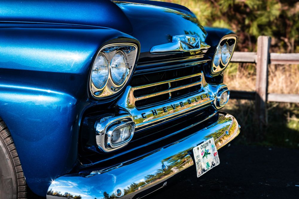 Close-up of classic blue Chevy truck grille and headlights.