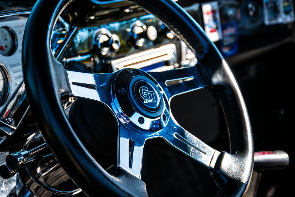 Chrome steering wheel of classic car interior with blue reflections.