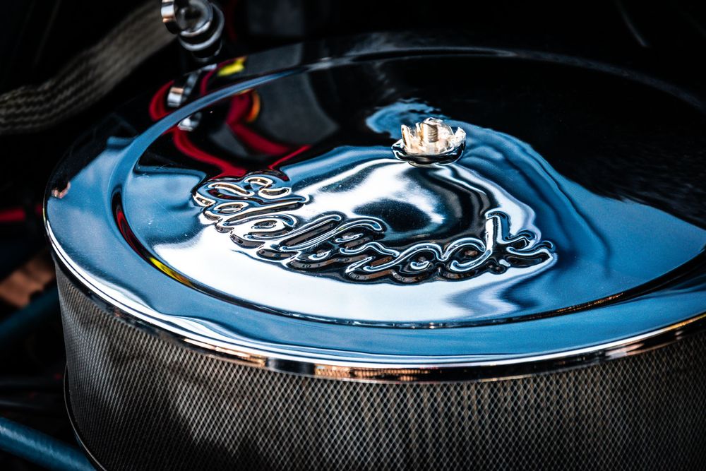 Chrome air filter cover on custom car engine with blue metallic finish.