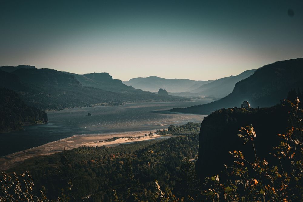 Dramatic sunset view of a mountainous valley with winding river and steep cliffs.