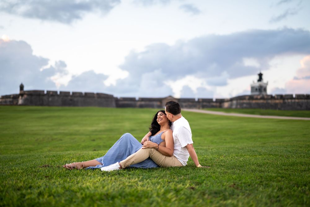 Couple relaxing on grassy lawn at El Morro fortress in San Juan, Puerto Rico during sunset.