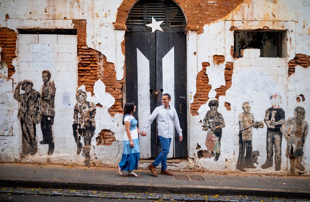 A panoramic mural on a weathered brick wall shows shadowy figures and abstract patterns against a rustic backdrop.