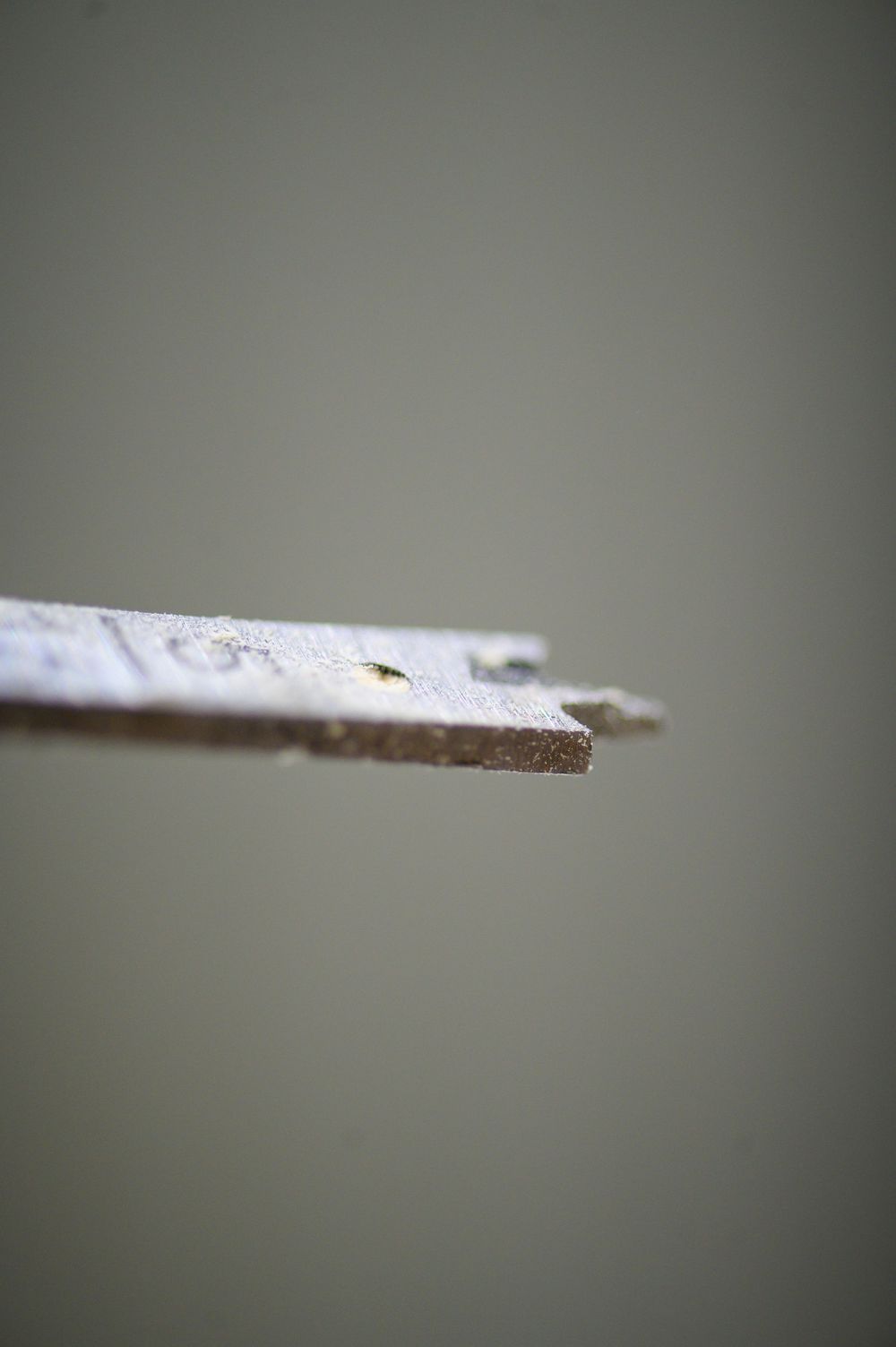 Close-up macro shot of a rough metal edge against a blurred gray background.