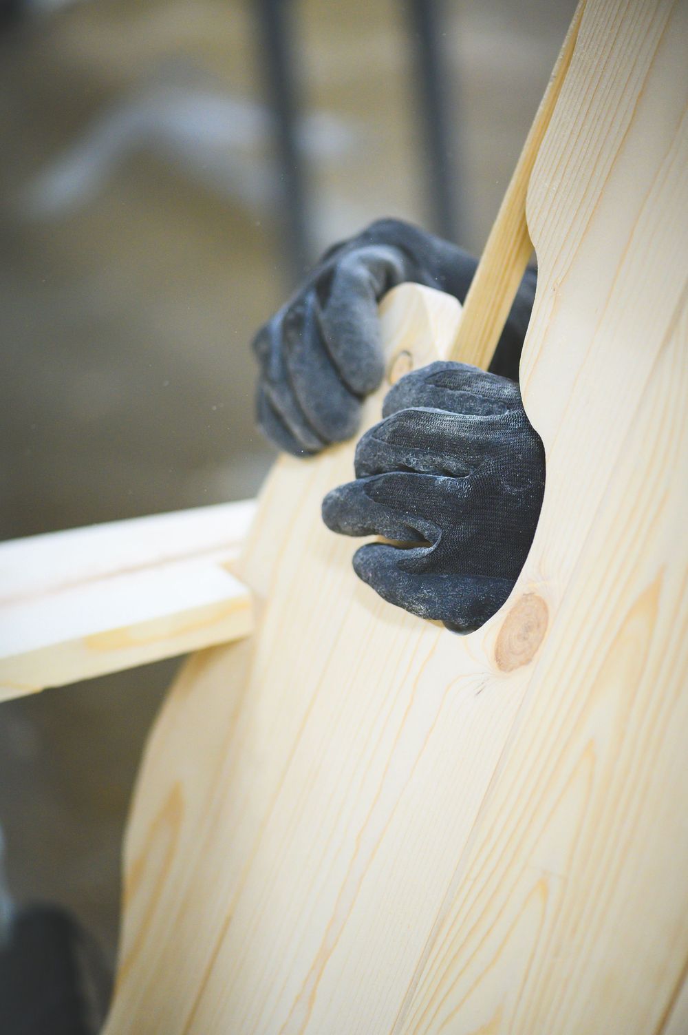 A black rubber gloved hand holds chair in the shape of Michigan thumb. Its backwards
