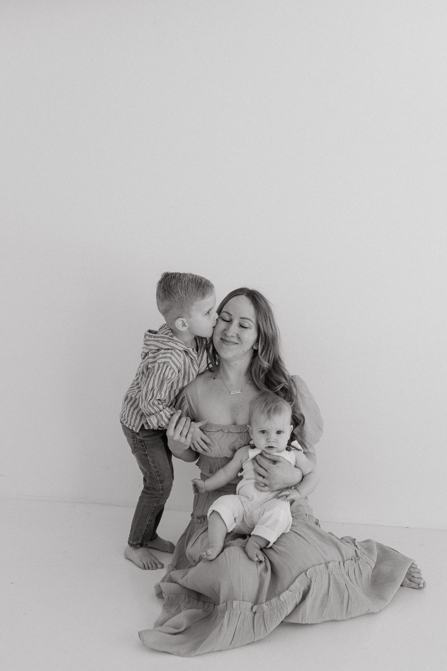 A sweet family photo series in muted tones shows tender moments between parent and children on a light backdrop.