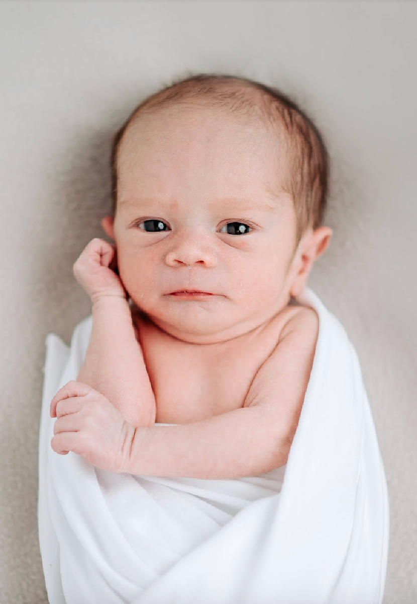 Sweet newborn photos show a baby wrapped in soft white fabric against a gray background, captured from different angles.