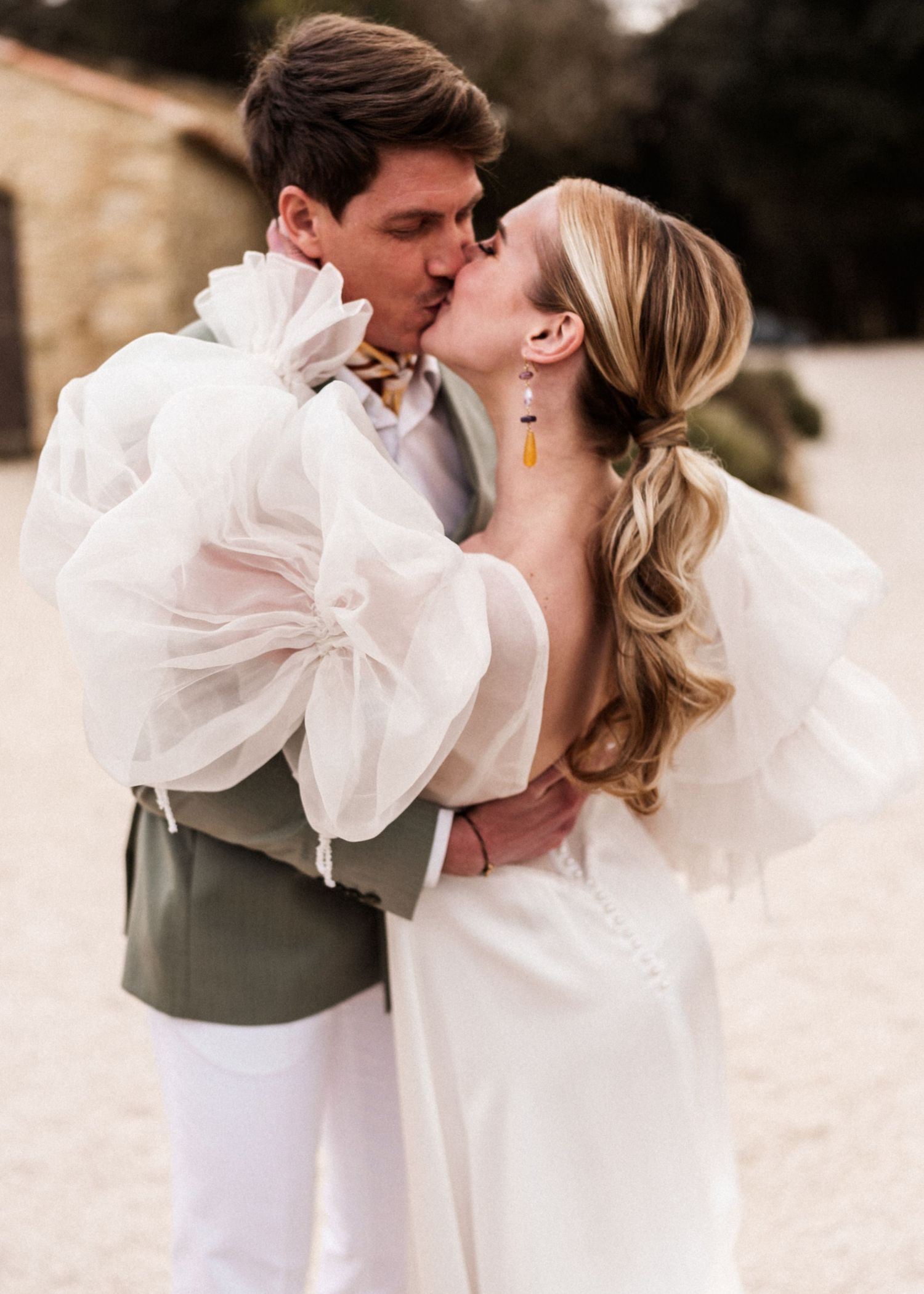 A romantic wedding portrait featuring the couple sharing a passionate kiss.