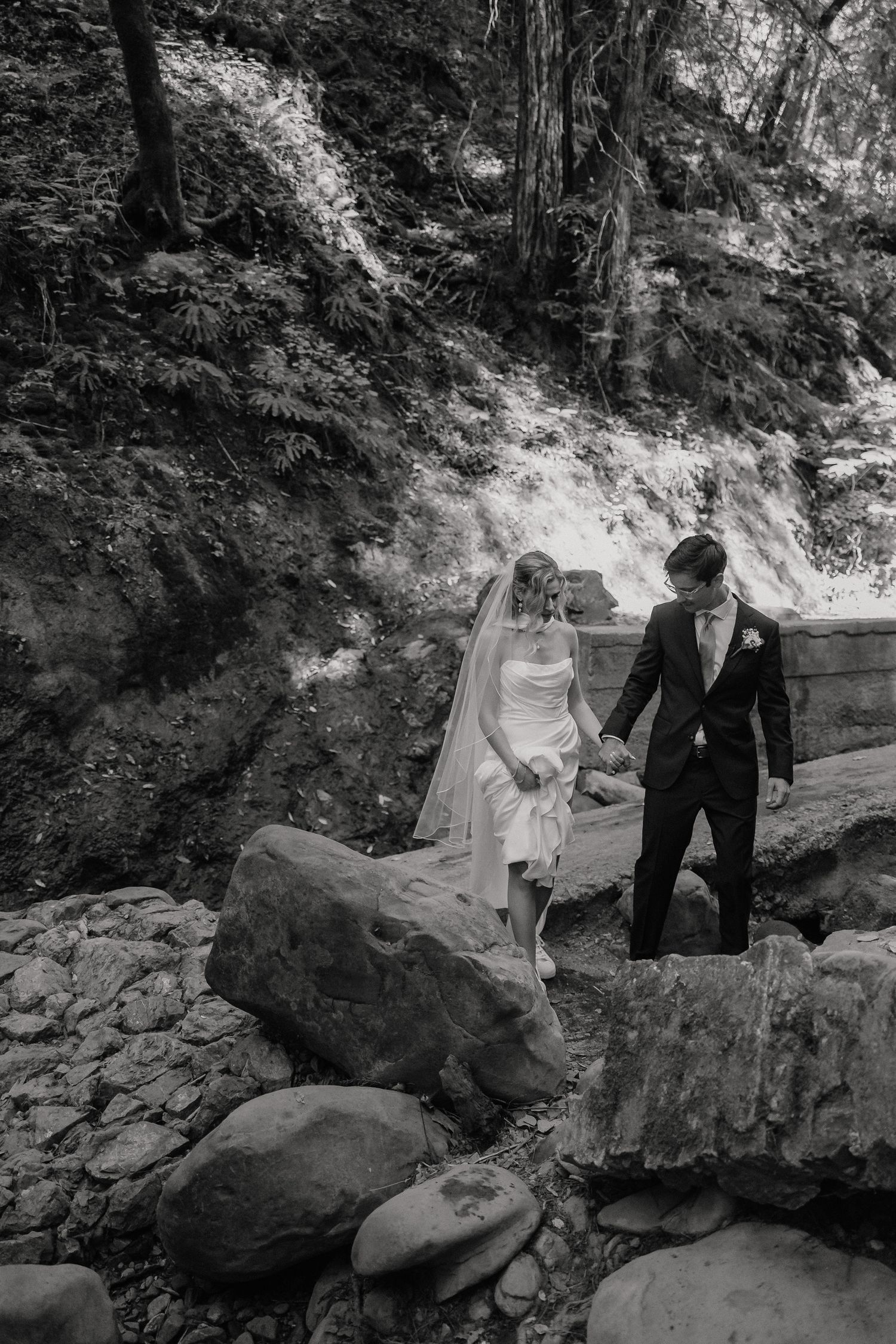 Black and white wedding portrait session on rocky terrain in a forest setting.