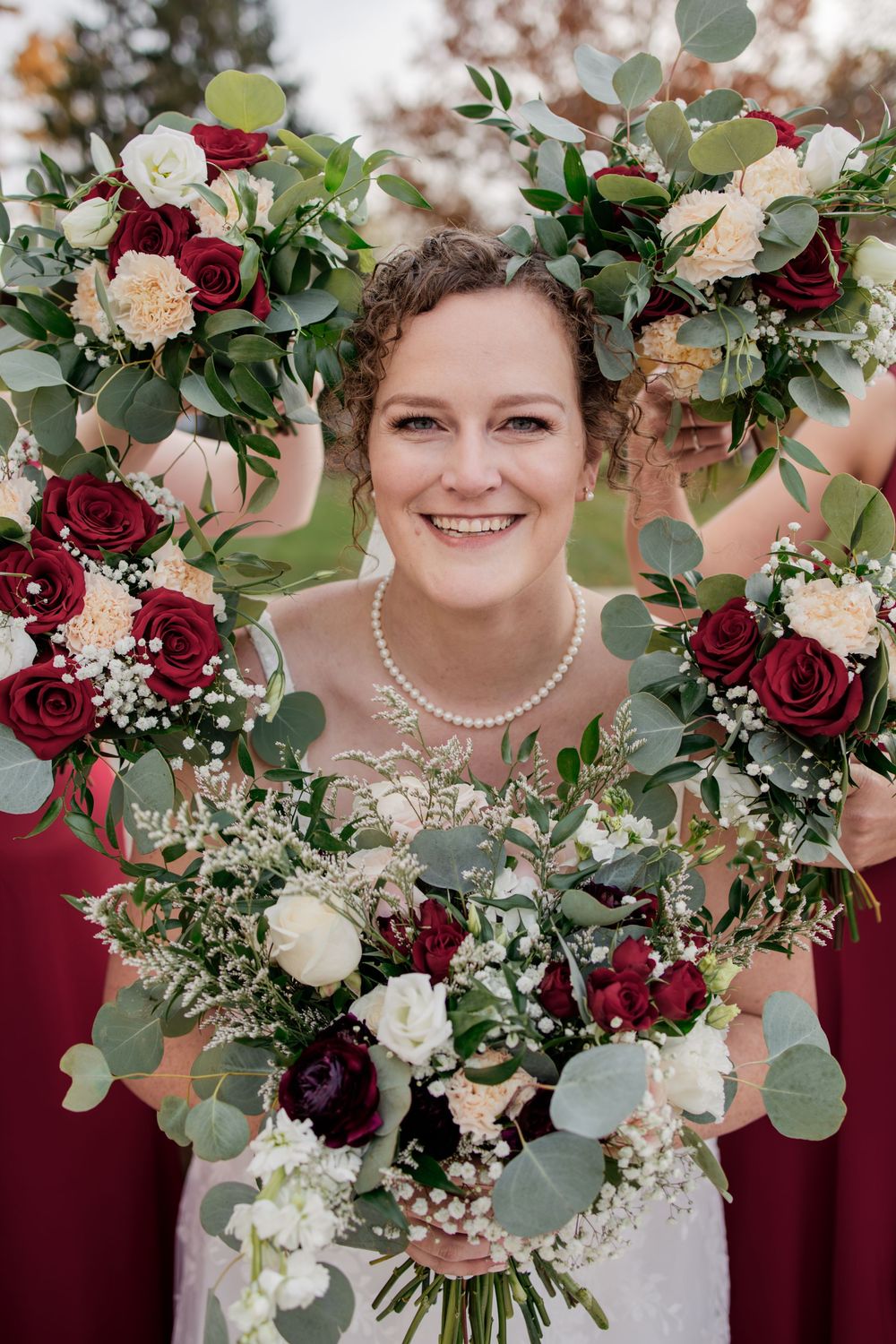 Beautiful bridal bouquet featuring deep red roses, white flowers and eucalyptus greenery.