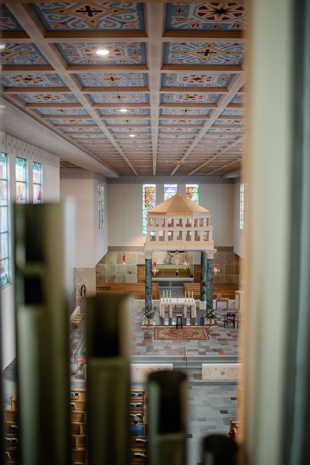 Interior of a modern church sanctuary with ornate ceiling details and stained glass windows.