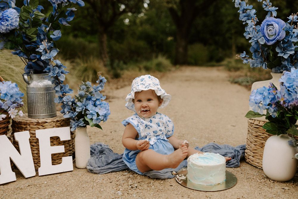 Rustic outdoor wedding decor featuring light blue hydrangeas and white ceramic vases arranged on a dirt path.