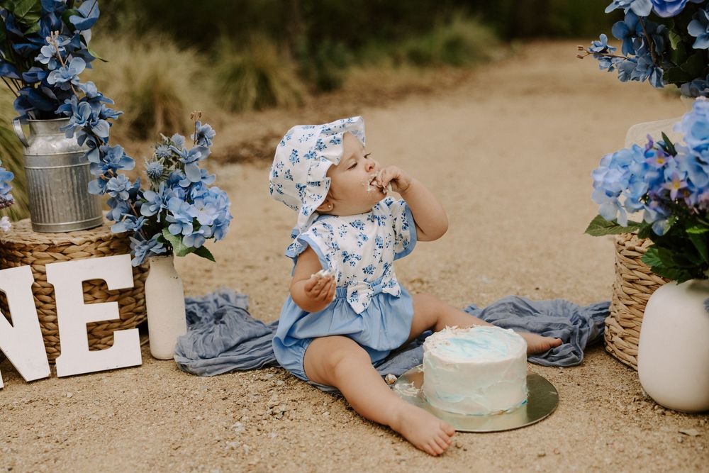 Light blue floral decorations and candles arranged on sandy ground create a romantic outdoor setting.