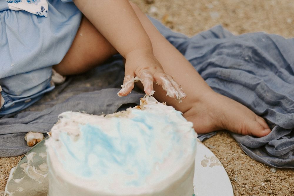 A sequence showing a baby diaper being changed on a sandy surface with a gray cloth nearby.