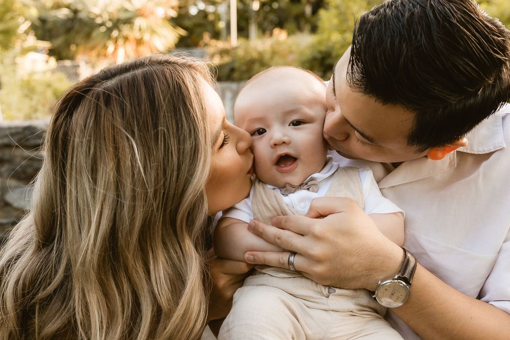 Baby smiling while being held by parents during an outdoor family session at Mt Coot-tha in Brisbane