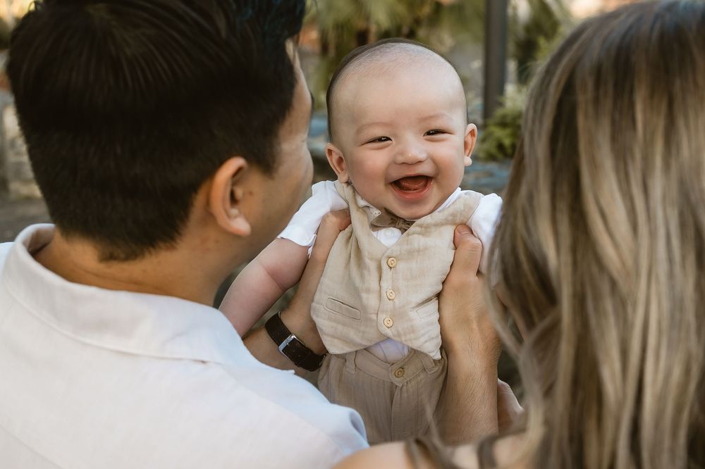 Parents kissing their baby on both cheeks during a sunset family photo shoot at Mt Coot-tha Botanic Gardens in Brisbane