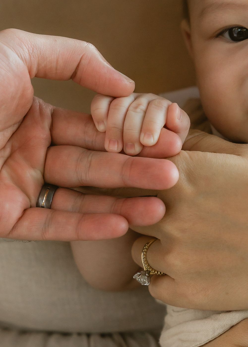 Close-up of a baby’s tiny hand holding onto mum and dad’s fingers during a Brisbane family session with Joanna Kate Photography.