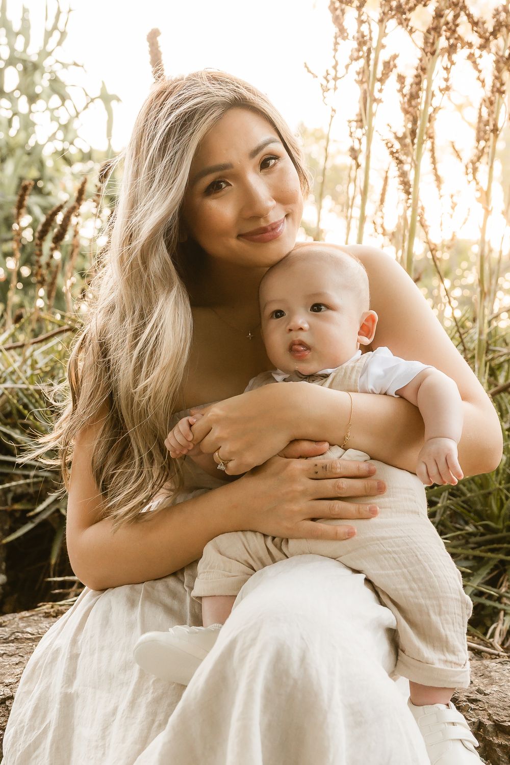 Mother holding her baby boy and smiling softly during golden hour at Mount Coot-tha, Brisbane, captured by Joanna Kate Photography.