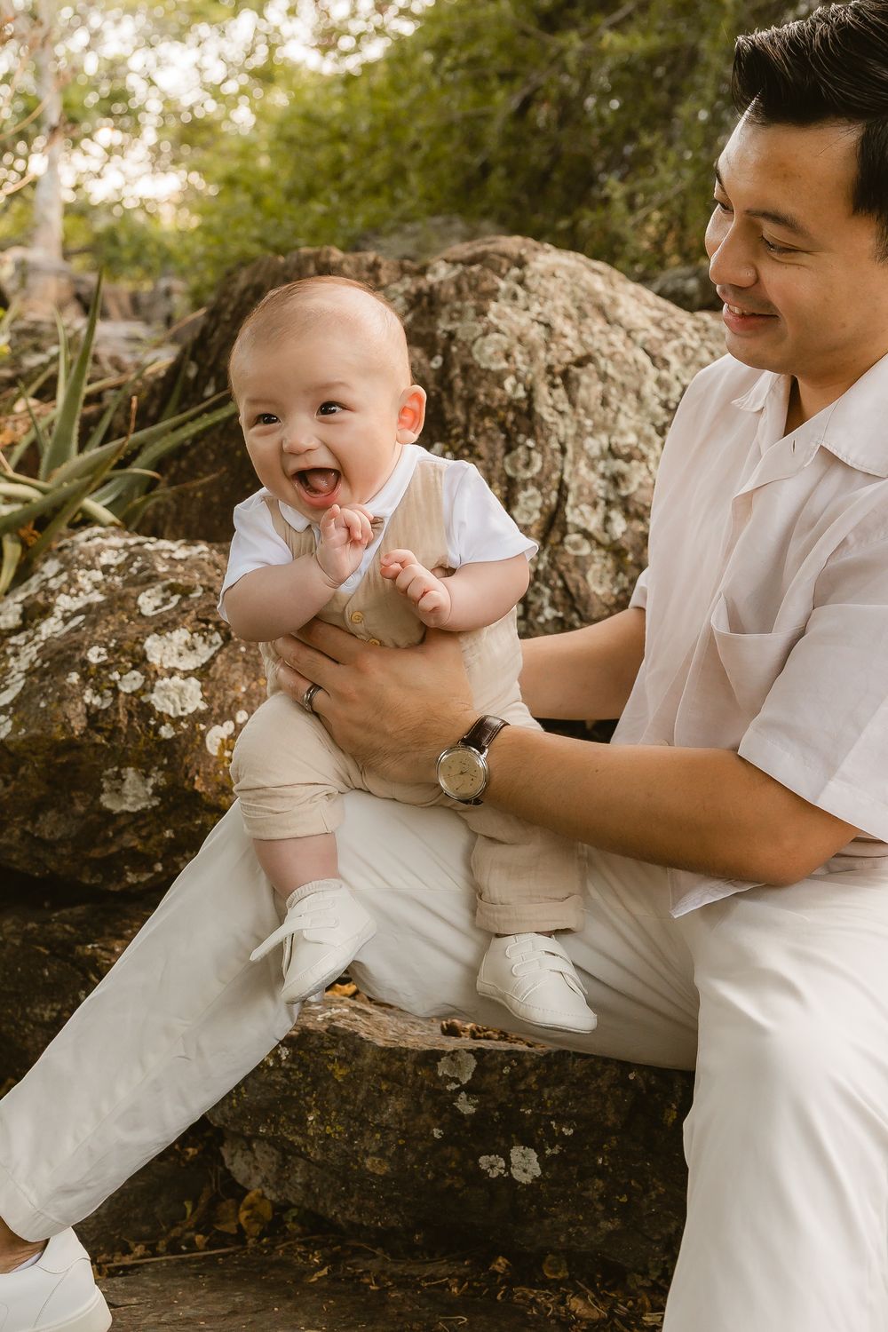 Father holding a laughing baby boy during a relaxed outdoor family photoshoot at Mount Coot-tha in Brisbane