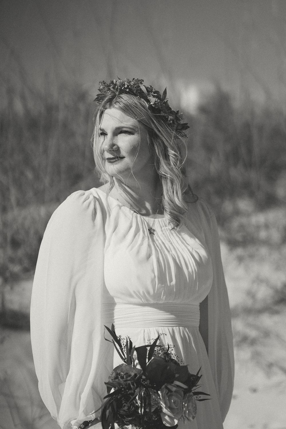 Ethereal black and white portrait of a bride in a vintage-style dress with puff sleeves against a dreamy background. Carolina Beach, NC