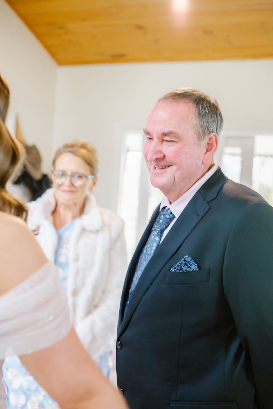 Emotional first look moment between family members at a wedding, with a wood-paneled ceiling in the background.