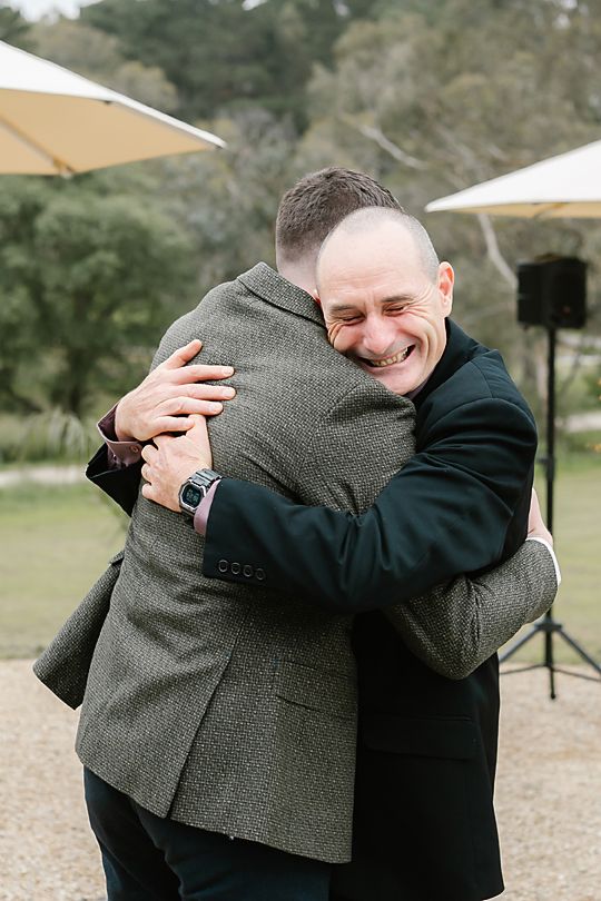 Heartwarming embrace between wedding attendees during an outdoor ceremony.