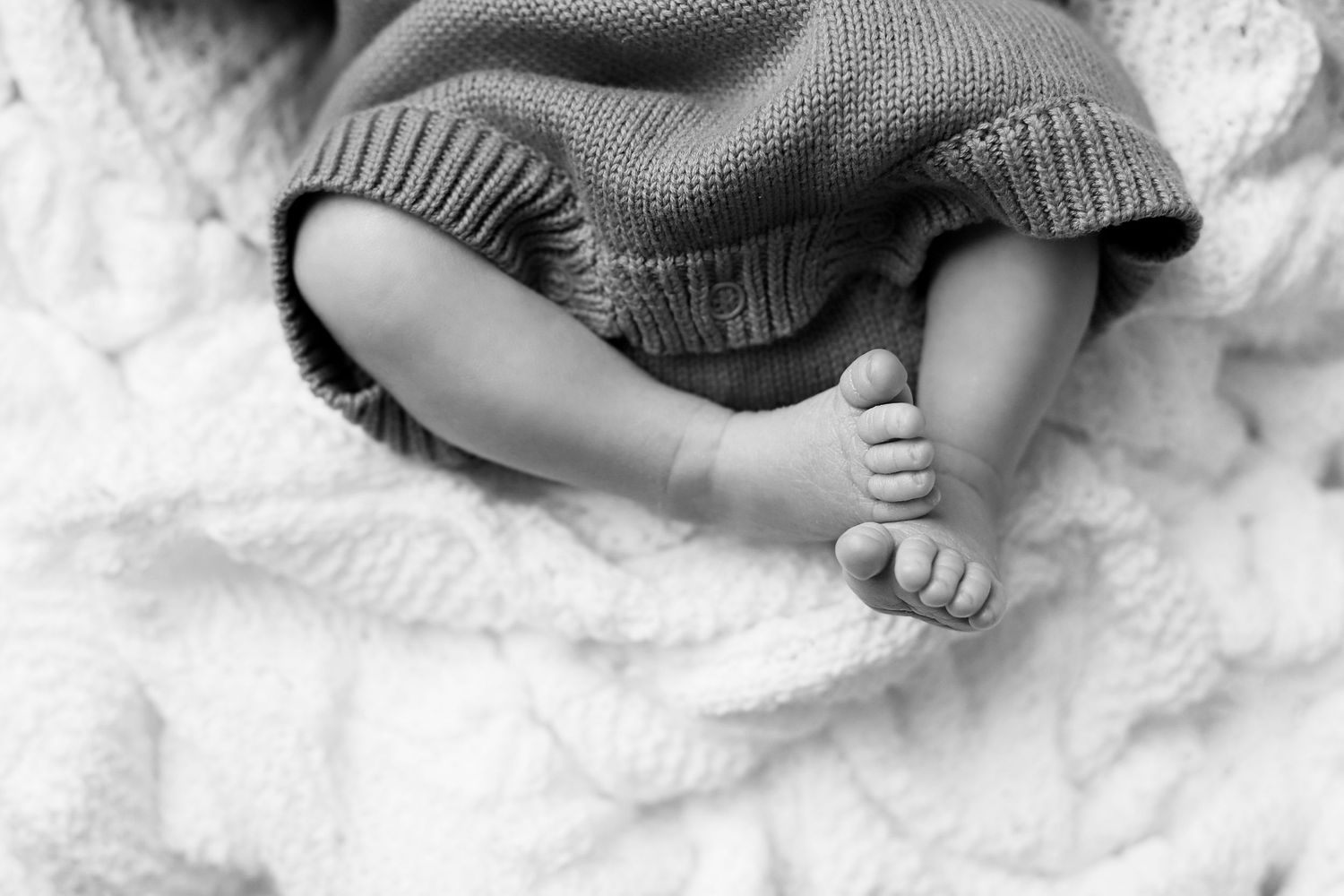A series of black and white photos showing tiny baby feet nestled in soft blankets and fabrics.