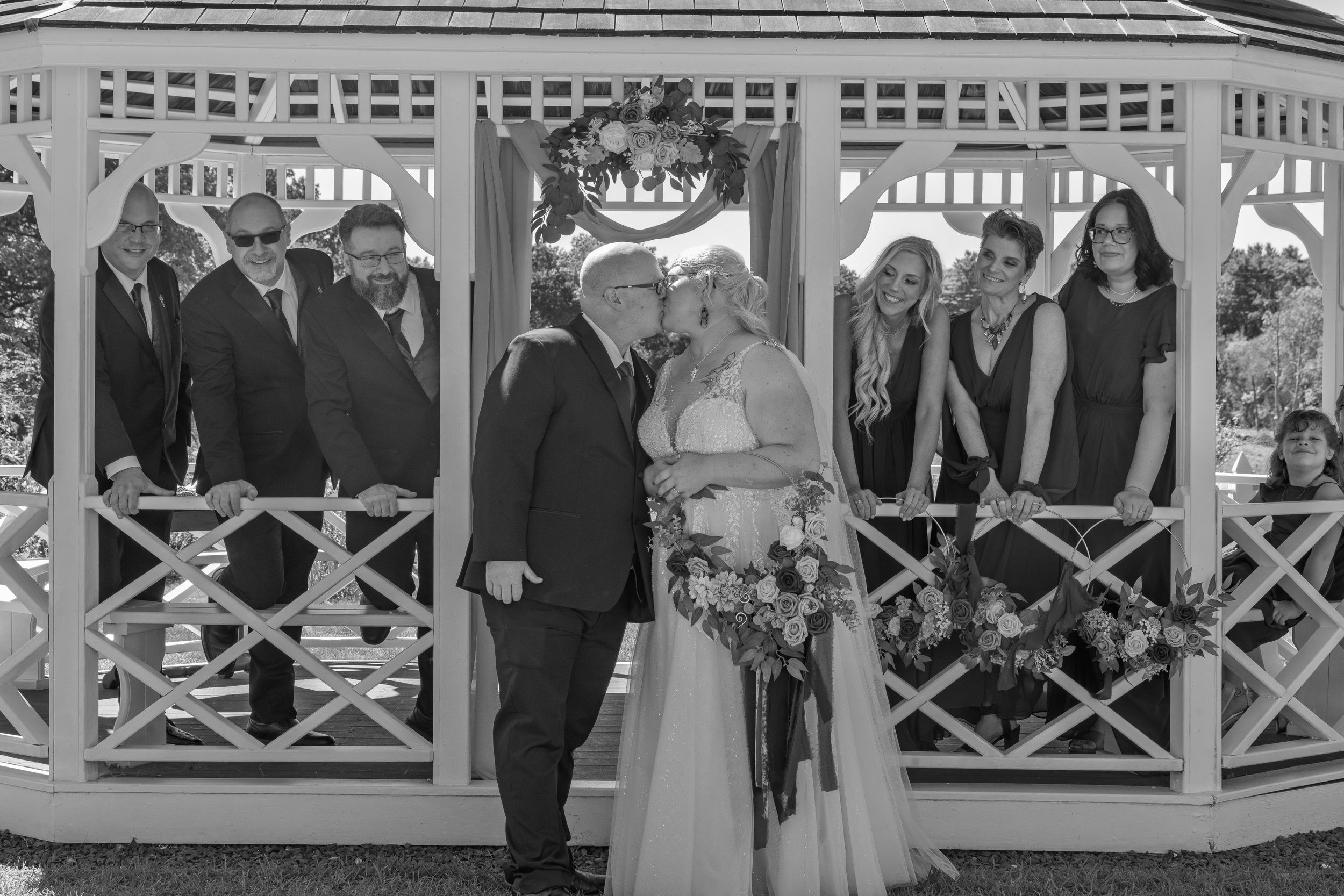 A series of black and white wedding photos showing couples and guests celebrating in an elegant gazebo setting.
